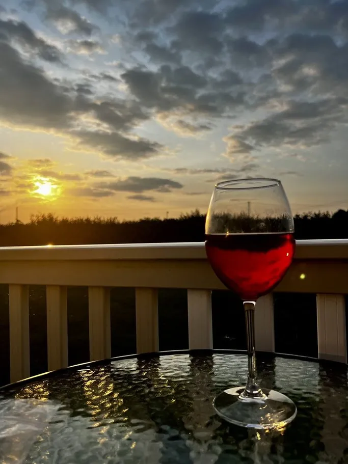 A glass of red wine at sunset on the decking at Meadow Lakes 76